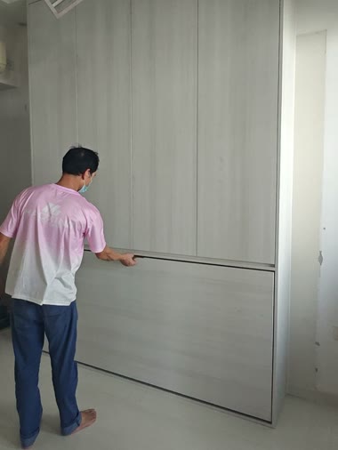 A completed full-height wardrobe wall in light wood with the Murphy bed closed flush into it.