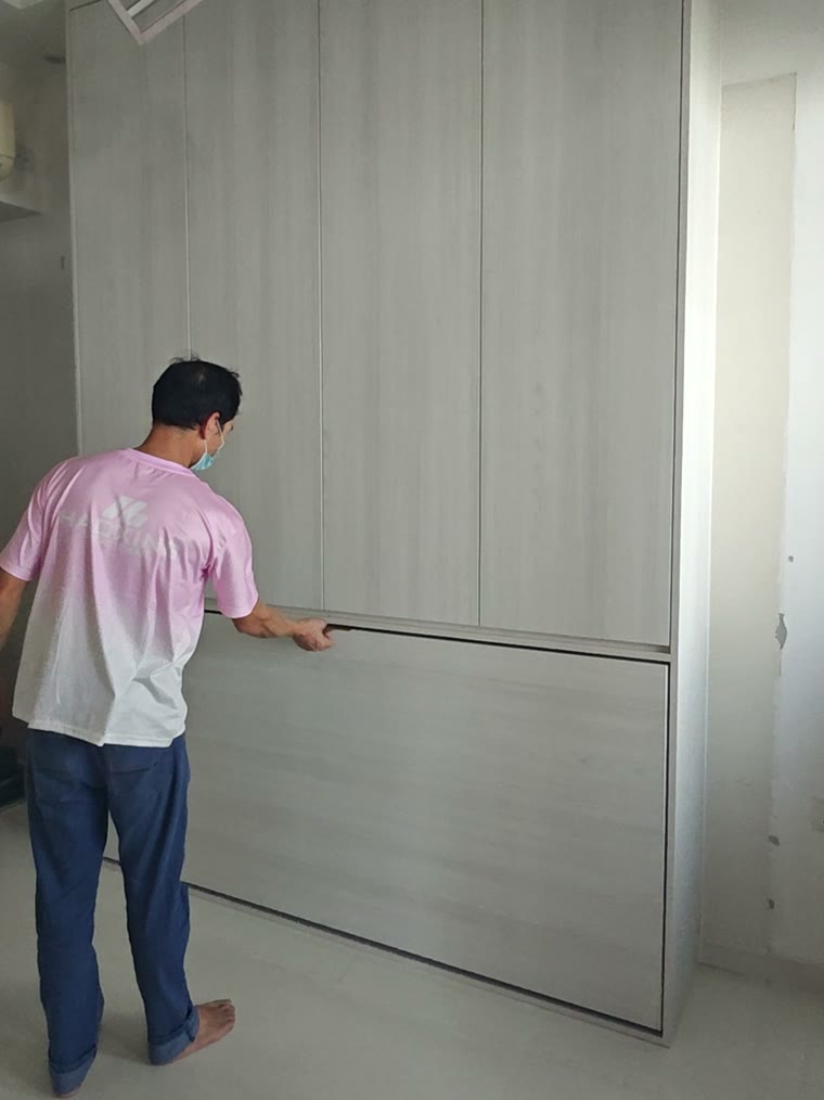 A completed full-height wardrobe wall in light wood, photographed as the Murphy bed closes flush into it.