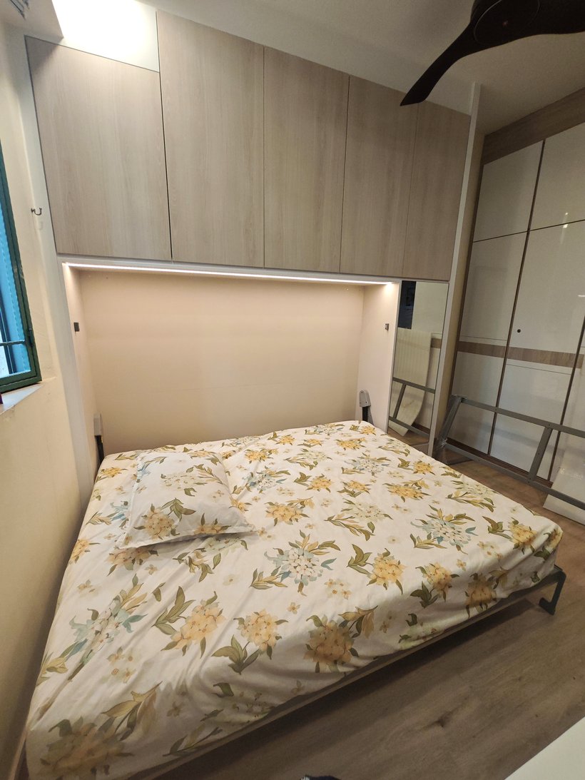 A completed manual Murphy bed being brought down from the wall by hand.