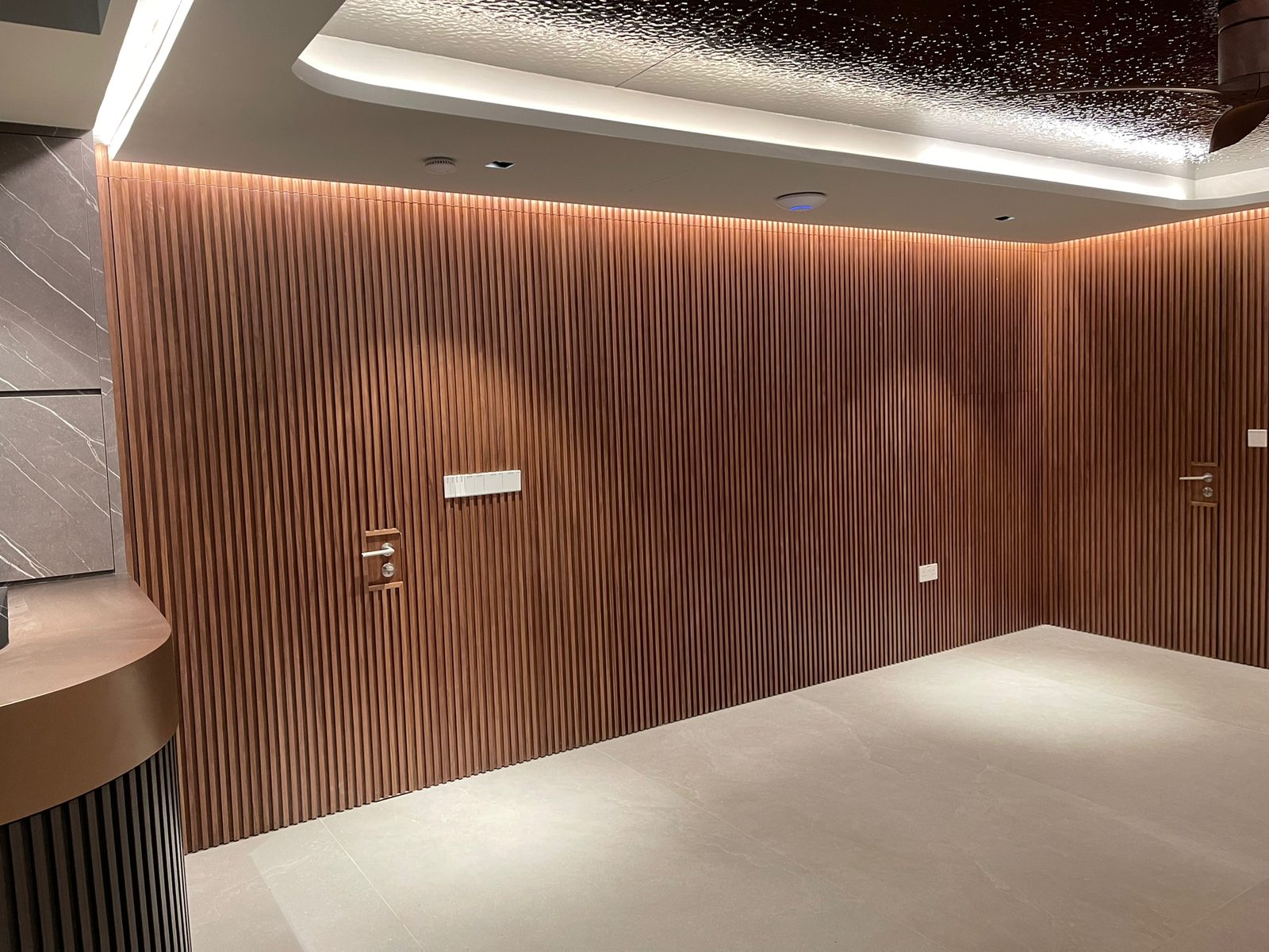 Full-height fluted walnut panelling with concealed flush doors in a landed home hallway
