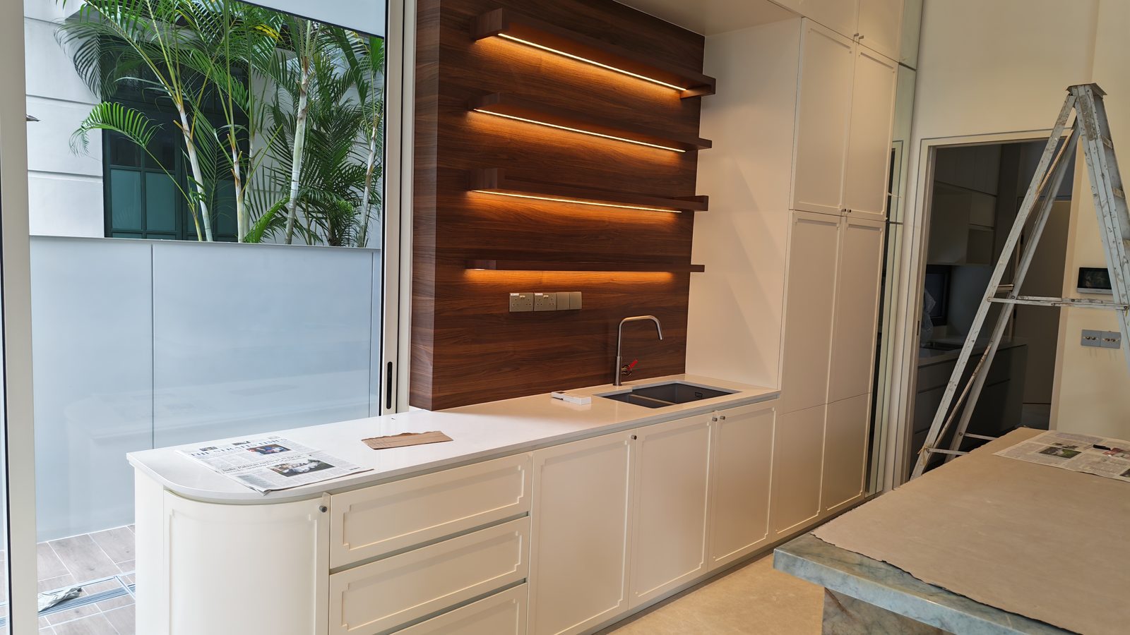 Shaker-style kitchen with a walnut feature wall and integrated LED shelving in a Singapore landed home